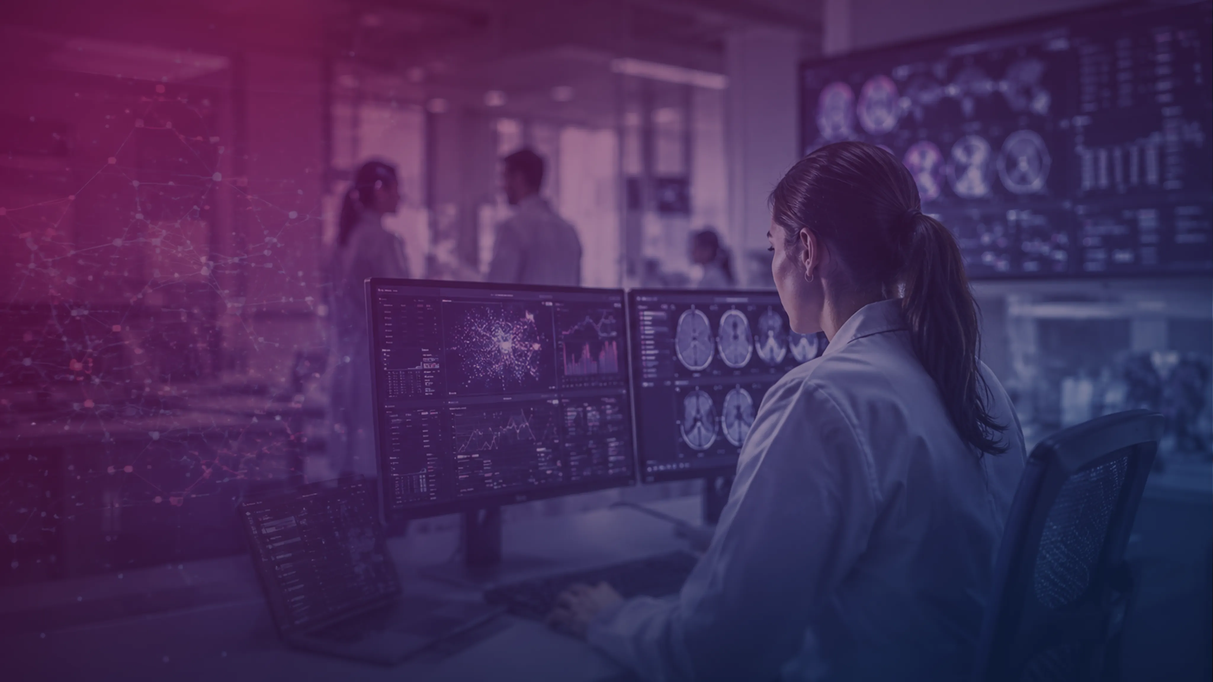 Una professionista sanitaria di spalle davanti a monitor con immagini radiologiche del cervello e grafici.